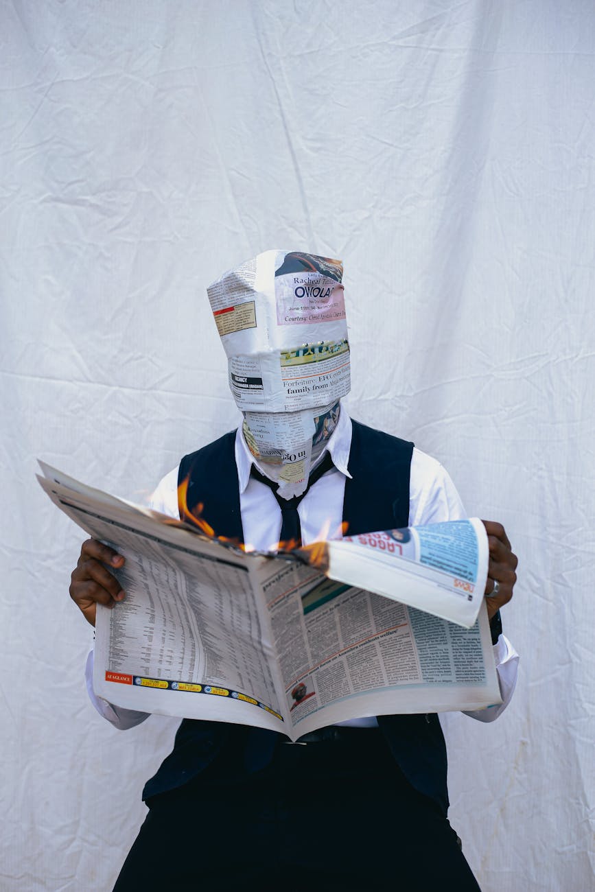 man with newspaper head holding burning newspaper